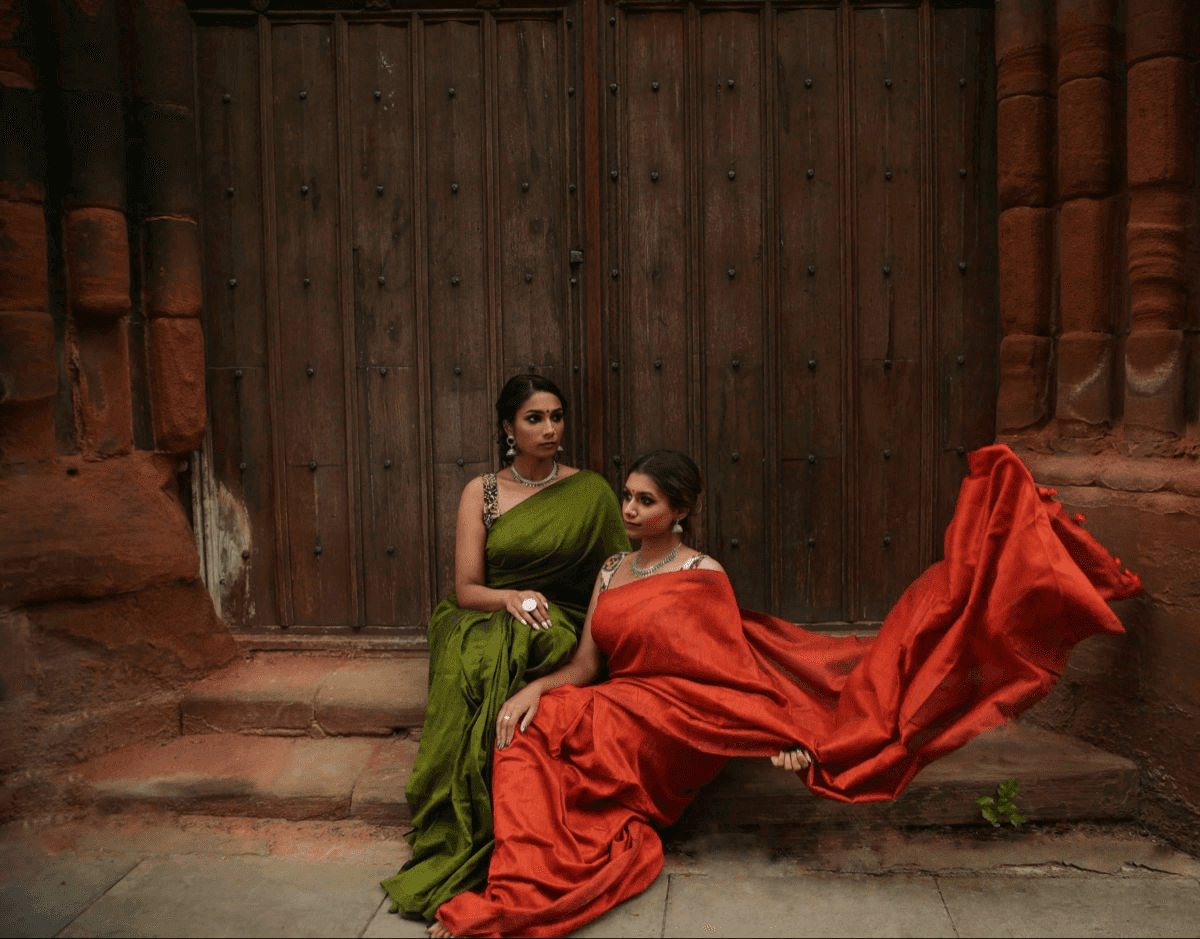 Two women in draped sarees and jewellery